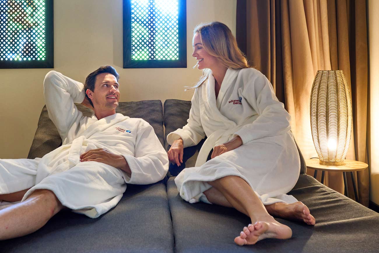 Sauna Ruhebereich mit lächelnden Pärchen auf Relax-Liegen