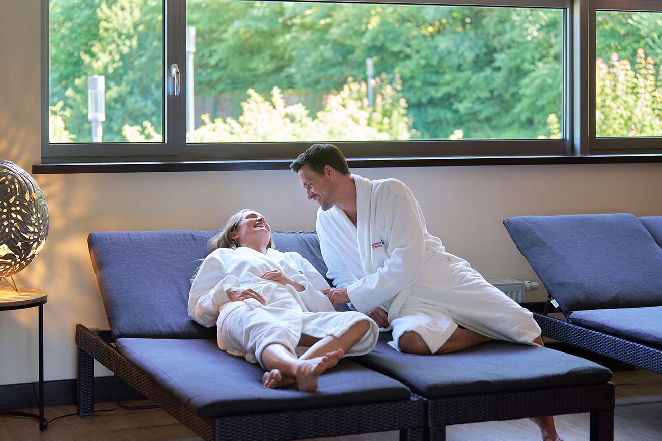 Sauna Ruheraum mit lachendem Pärchen auf Relax-Liegen