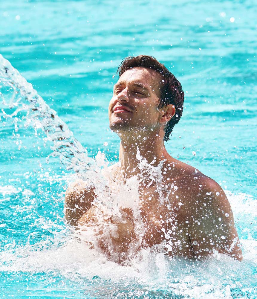 Mann genießt die Massage einer Wasserfontaine